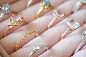 A couple’s hands together, each wearing distinctive, modern wedding bands with mixed metals and subtle texture.